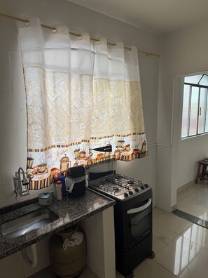 A kitchen with a gas stove, sink, and a window with a view.