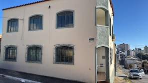 Un edificio de dos pisos con varias ventanas, una entrada con reja y una vista despejada del entorno urbano.