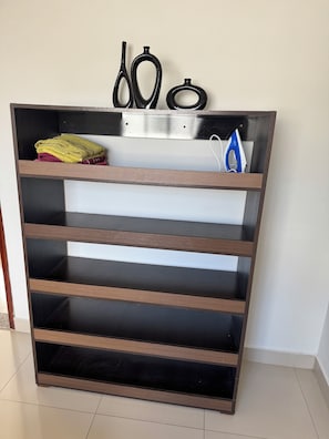 Una estantería de madera con varios compartimentos, algunos con toallas dobladas y un par de tijeras.