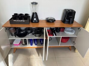 A kitchen with a wooden countertop, a blender, a coffee maker, and various kitchen utensils and cookware.