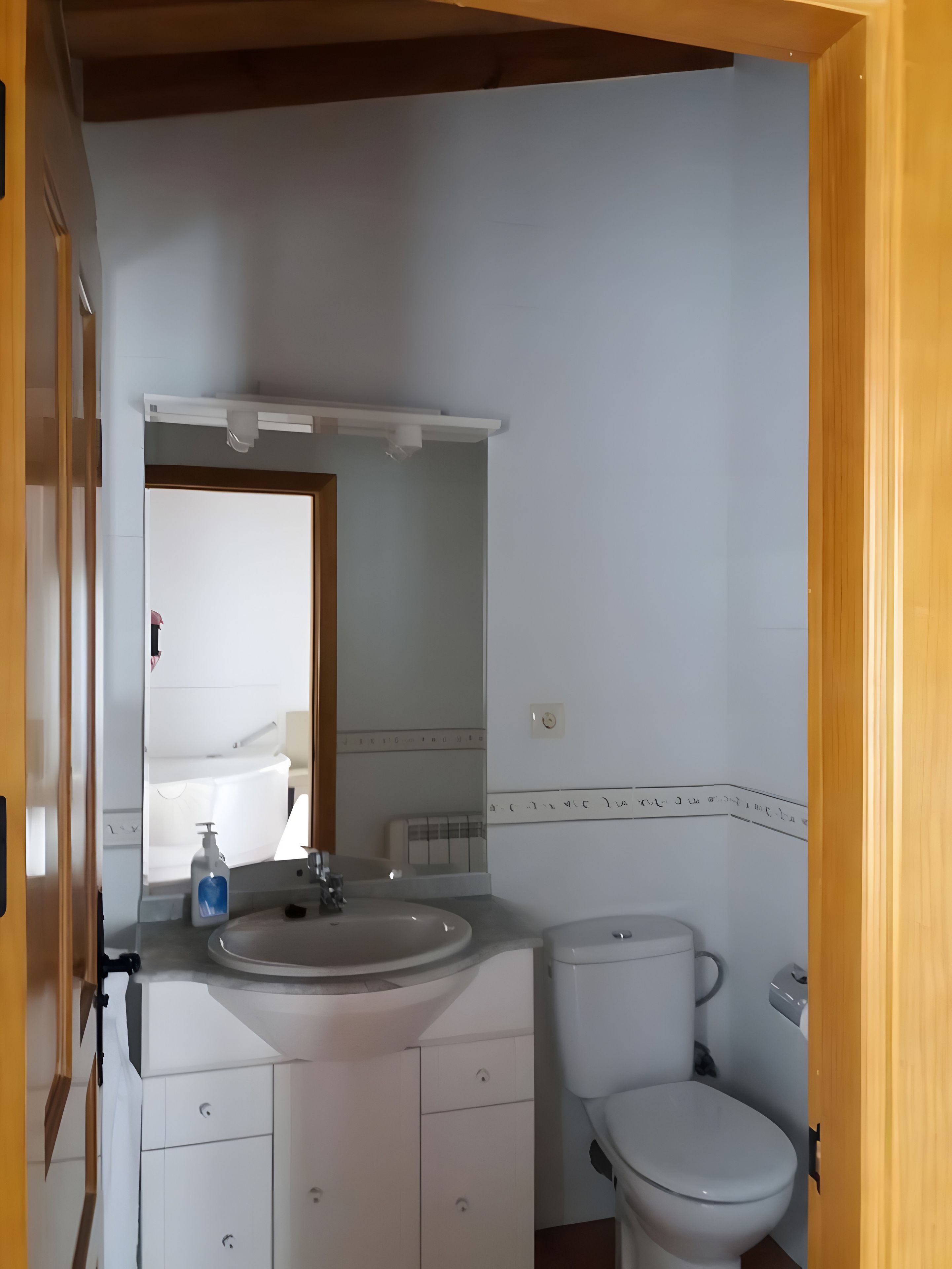 A bathroom with a white sink, mirror, and toilet.