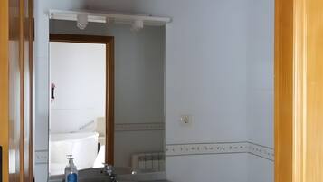 A bathroom with a white sink, mirror, and toilet.