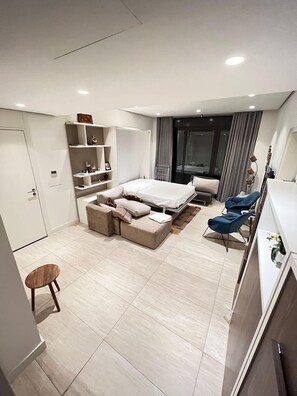 A modern bedroom with a bed, seating area, and a desk.