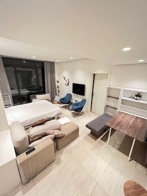 Una habitación de hotel moderna con cama, sofá, televisor y escritorio.