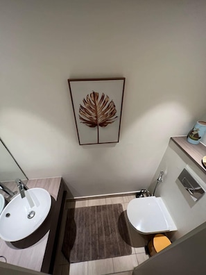 Un baño con dos lavamanos, un espejo, una obra de arte con una hoja enmarcada y un perchero para toallas.