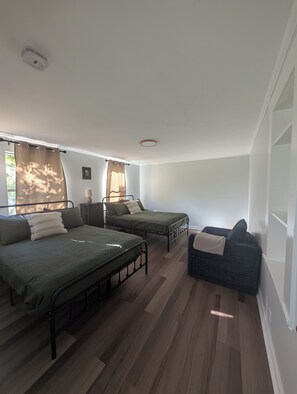 Una habitación con dos camas, una ventana con cortinas, una mesita de noche y una lámpara fijada a la pared.