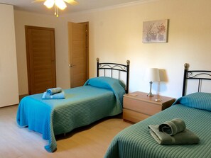 A room with two beds, a nightstand, a lamp, and a painting on the wall. - Villa 'Miramar Burriana Nerja' with Sea View, Wi-Fi and Air Conditioning (Nerja)