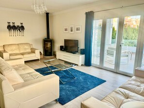 Ein modernes Wohnzimmer mit einer Couch, einem Glastisch, einem Fernseher und einem Kamin.