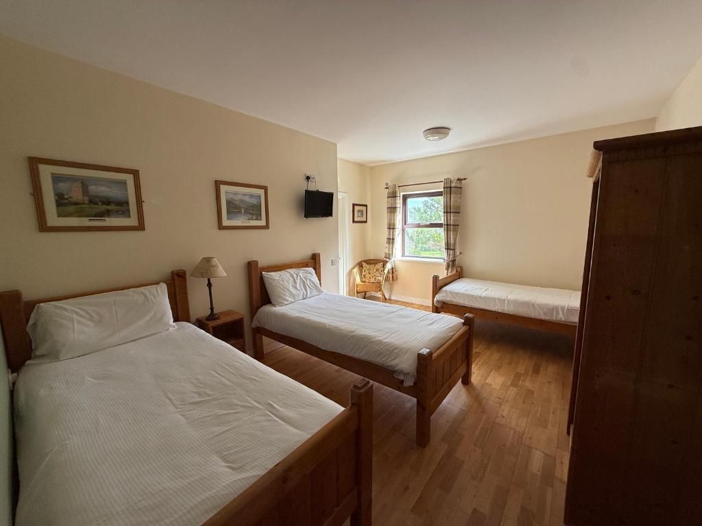 A room with two wooden beds, a wooden wardrobe, and a window with curtains.