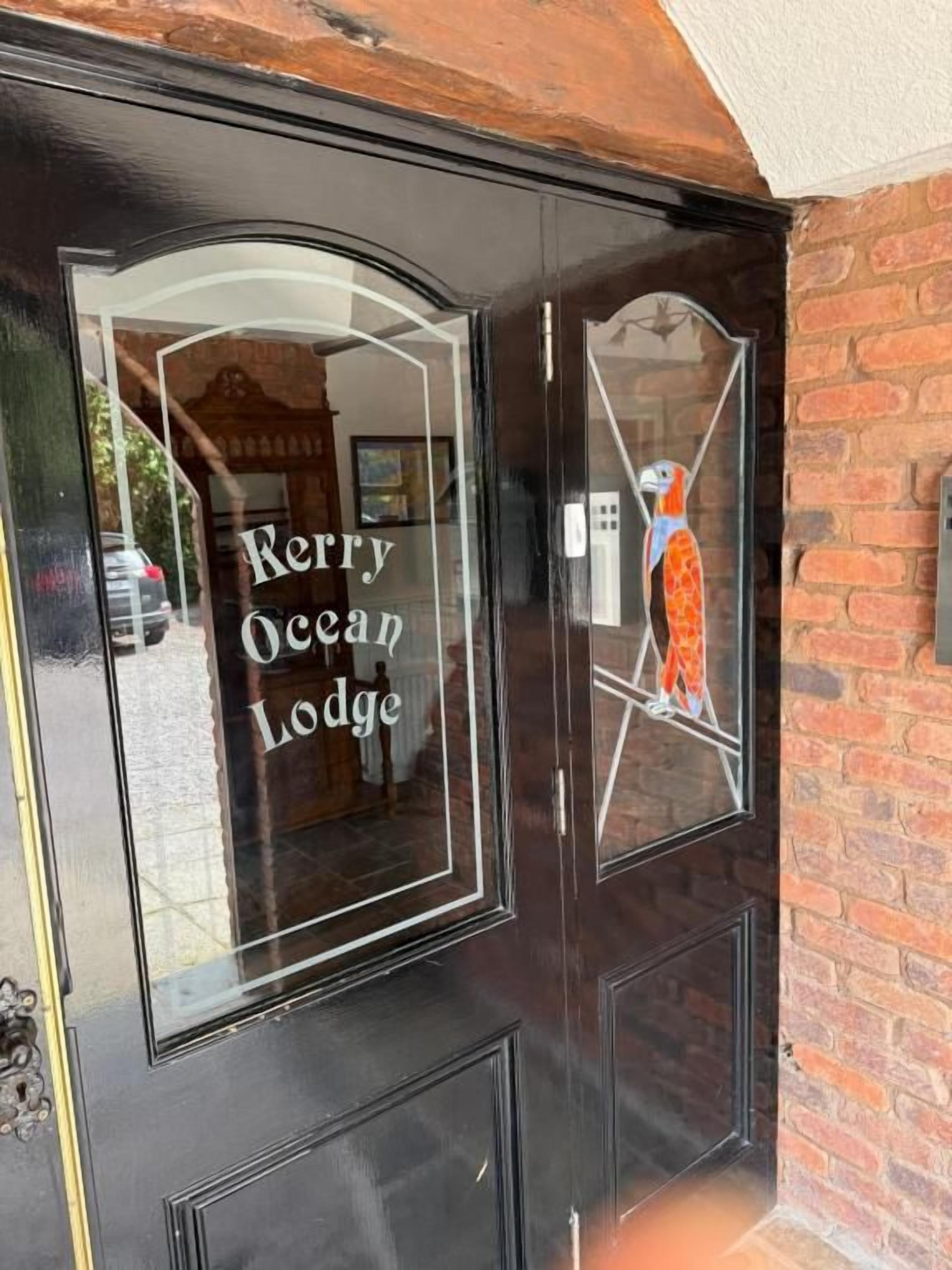 Une porte noire avec l’inscription « Kerry Ocean Lodge » et un vitrail décoratif.