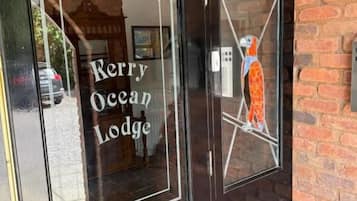 Une porte noire avec l’inscription « Kerry Ocean Lodge » et un vitrail décoratif.