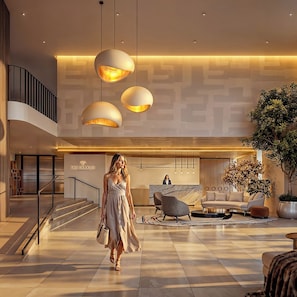 A modern hotel lobby with a central seating area, a staircase, and a reception desk. - The Charles (Somerset West, Cape Town)