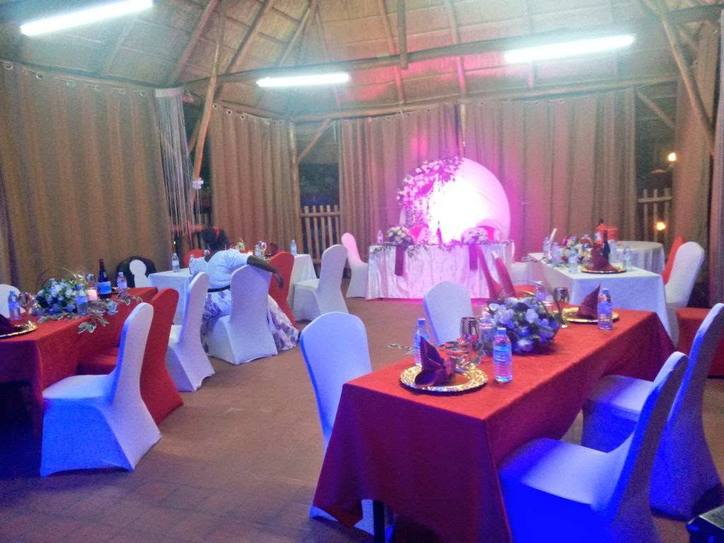 Un espacio interior para eventos con mesas dispuestas para una recepción, con sillas blancas y manteles rojos.