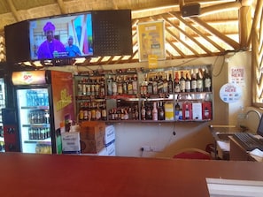 Een bar met een televisiescherm, drankenkasten en een bord waarop staat dat er met pinpas betaald kan worden.