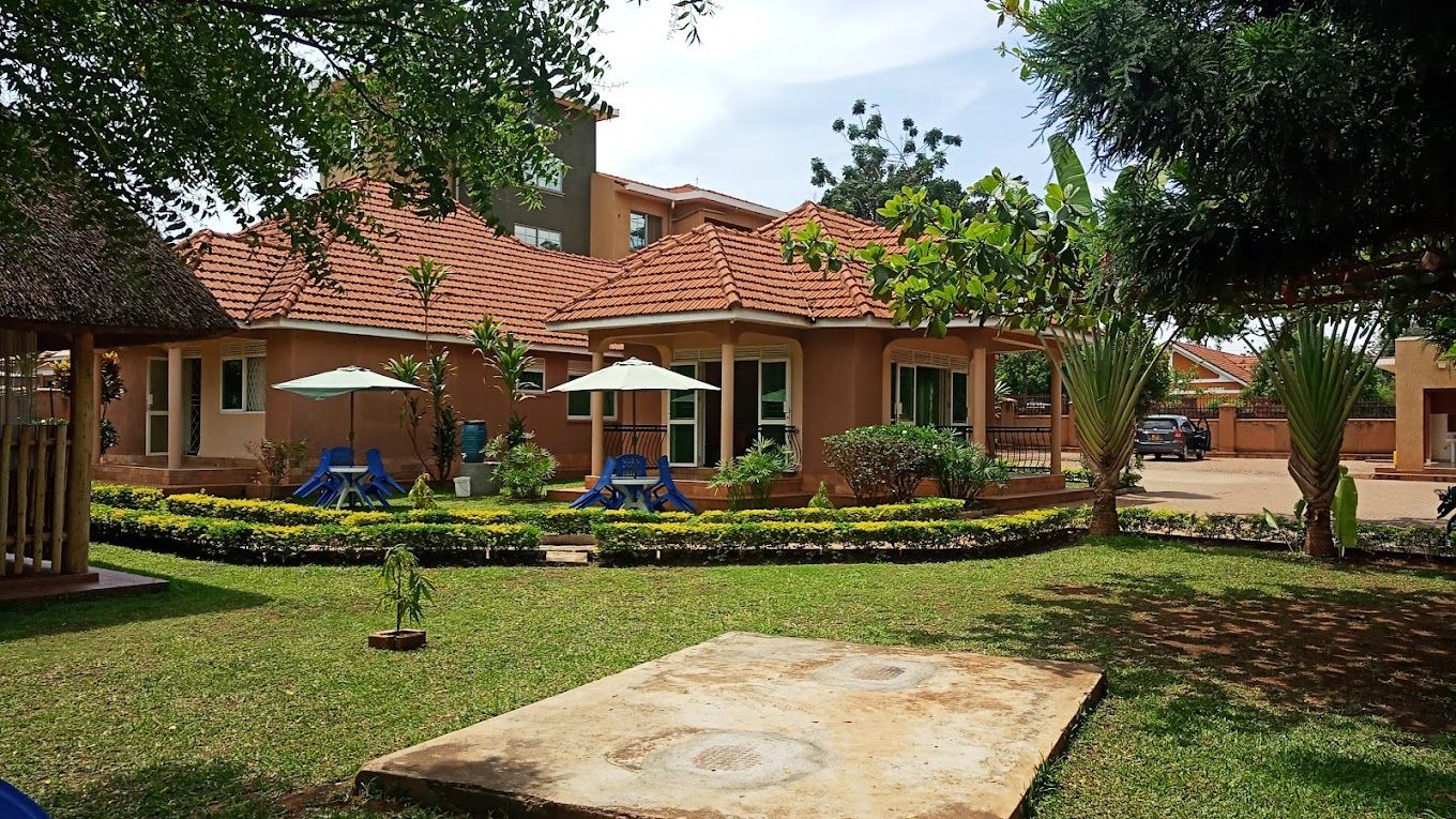 Un edificio residencial con techo de tejas, un jardín con zona de juegos y un patio de hormigón.