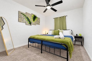 Ein Schlafzimmer mit Bett, Nachttisch, Deckenventilator und Bildern an der Wand.