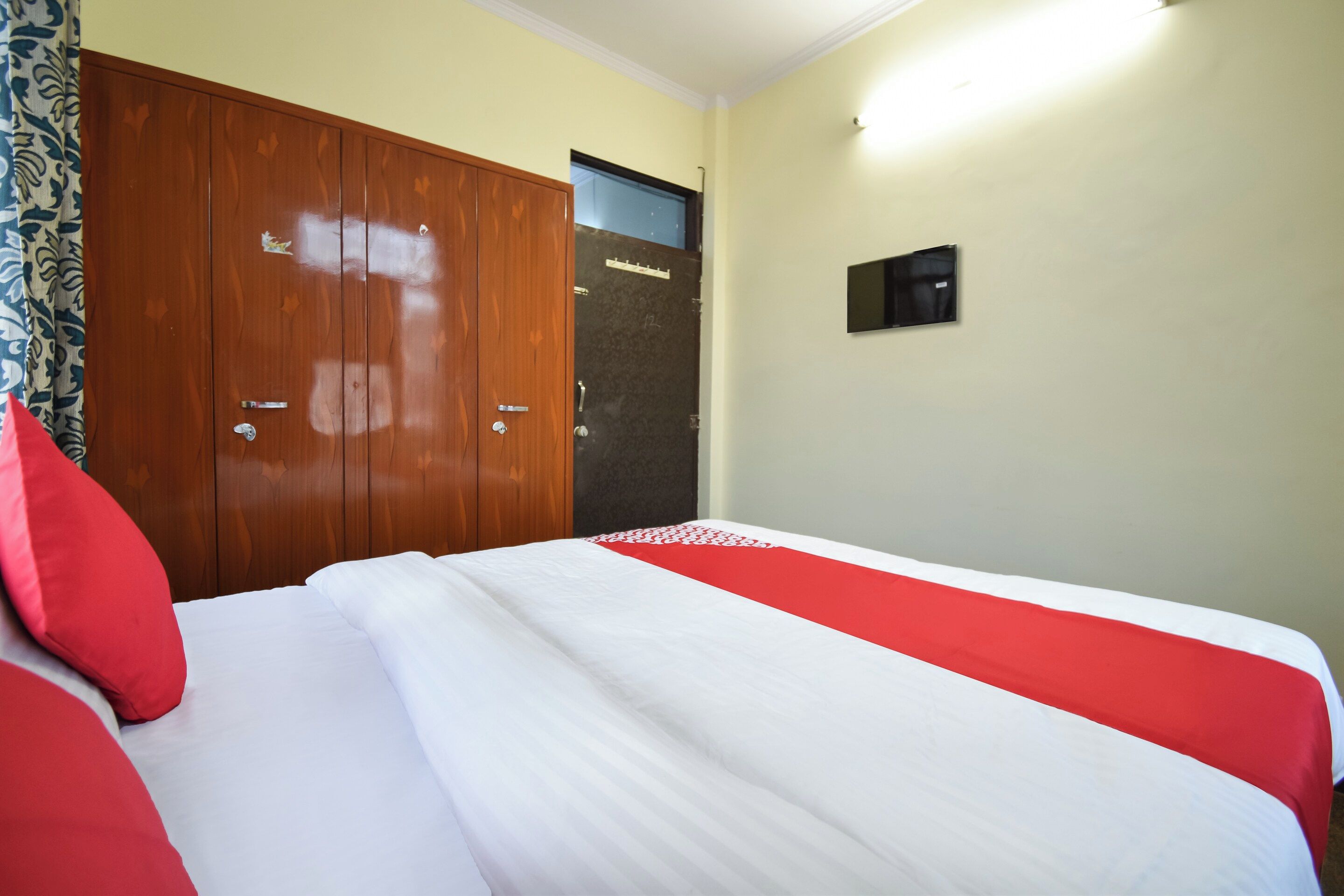 A hotel room with a large bed, a wardrobe, and a door.