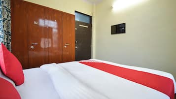 A hotel room with a large bed, a wardrobe, and a door.