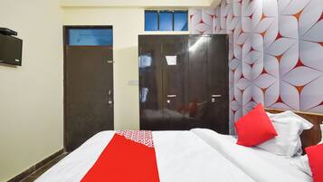 A hotel room with a bed, a wardrobe, and a door.