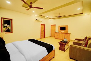 Ein Hotelzimmer mit Bett, Schreibtisch, Stuhl, Fernseher und Deckenventilator.