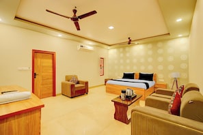 Ein Hotelzimmer mit einem Bett, einem Sofa, einem Schreibtisch, einem Stuhl, einem Deckenventilator und einer Klimaanlage.
