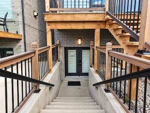 Una escalera con barandillas de madera y una puerta negra con placa de número.