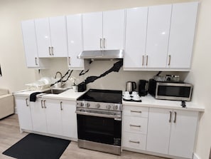 Una cocina moderna con gabinetes blancos, electrodomésticos de acero inoxidable y un salpicadero de encimera negro.