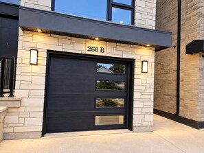 A modern building with a dark-colored garage door, numbered 266 B, and a light-colored brick facade.