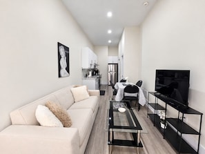 Un apartamento moderno con sala de estar, comedor, kitchenette y televisor.