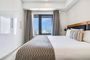 A hotel room with a large bed, a wardrobe, and a view of the cityscape. - Harbour Glimpses Central CBD Stay with Pool and Gym (Darwin)