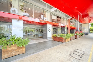 A modern building with glass storefronts, outdoor seating, and potted plants. - Harbour Glimpses Central CBD Stay with Pool and Gym (Darwin)