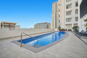A rooftop swimming pool with a diving board, surrounded by modern buildings and a clear sky. - Harbour Glimpses Central CBD Stay with Pool and Gym (Darwin)