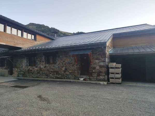 A stone building with a metal roof, a wooden deck, and a gravel driveway.