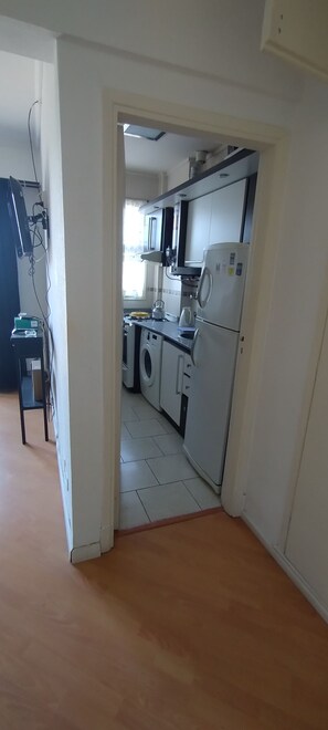 Eine Küche mit Waschmaschine, Kühlschrank und Mikrowelle.