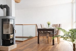 Un interno moderno con stufa a legna, tavolo da pranzo con sedie e una pianta in vaso.