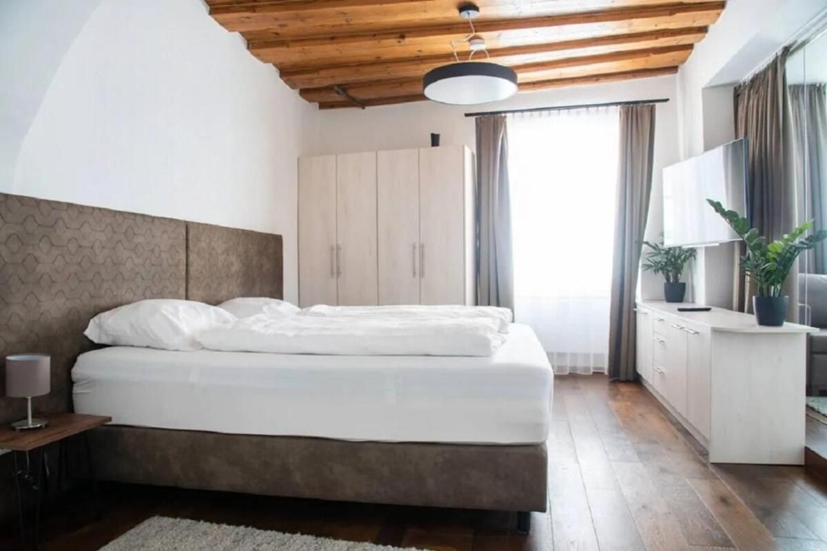 Una camera da letto con un letto, un armadio, una scrivania, una lampada e una finestra con tende.