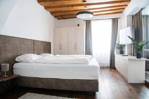 A bedroom with a bed, a wardrobe, a desk, a lamp, and a window with curtains. - Urban Luxury Apartments (Graz)