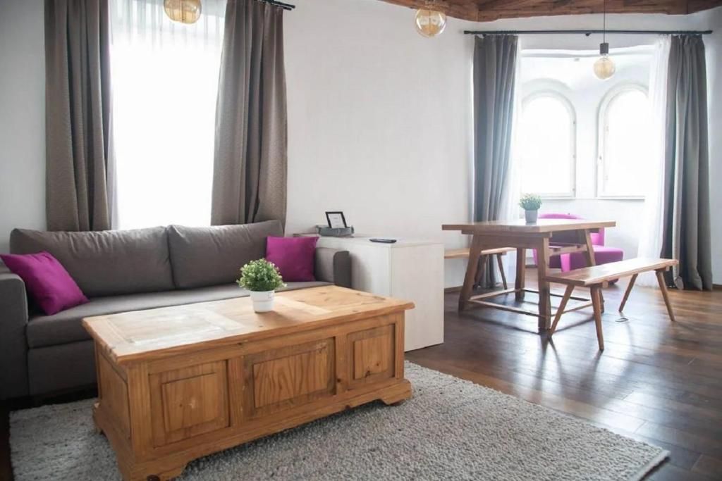 Un salon comprenant un canapé, une table basse et un coin repas avec un banc.