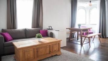 Un salon comprenant un canapé, une table basse et un coin repas avec un banc.