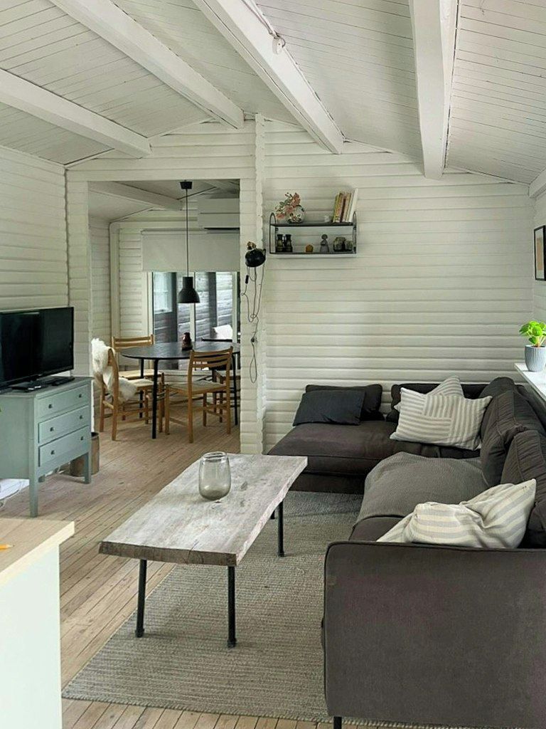 A living room with a sofa, a coffee table, a television, and a dining area with chairs and a table.