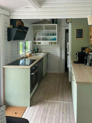 Een compacte keuken met een centraal eiland, inbouwapparatuur en een prikbord aan de muur.