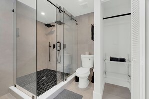 Een moderne badkamer met een douchecabine van glas, een wit toilet en een handdoekhouder.