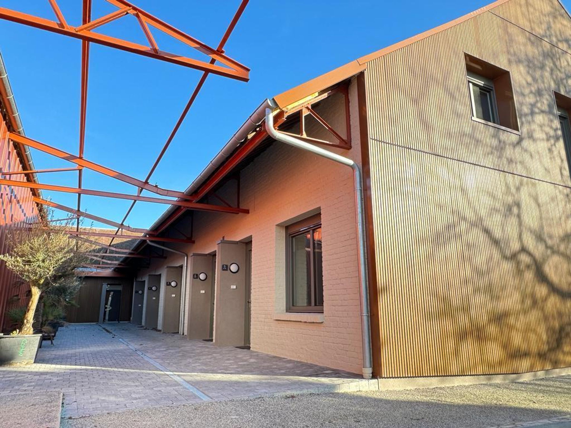 Un bâtiment à l’architecture moderne, comprenant une série de pièces, chacune étant dotée d’une porte portant un numéro distinct.