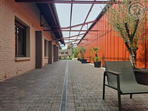 A covered walkway with brick flooring, potted plants, and a bench. - Ground-floor apartment near Cambrai - 4 guests (NIERGNIES)