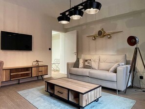 Una sala moderna con sofá, mesa de centro, televisor y un reloj decorativo.
