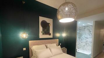A bedroom with a bed, two bedside lamps, a wall-mounted light fixture, and a framed picture.
