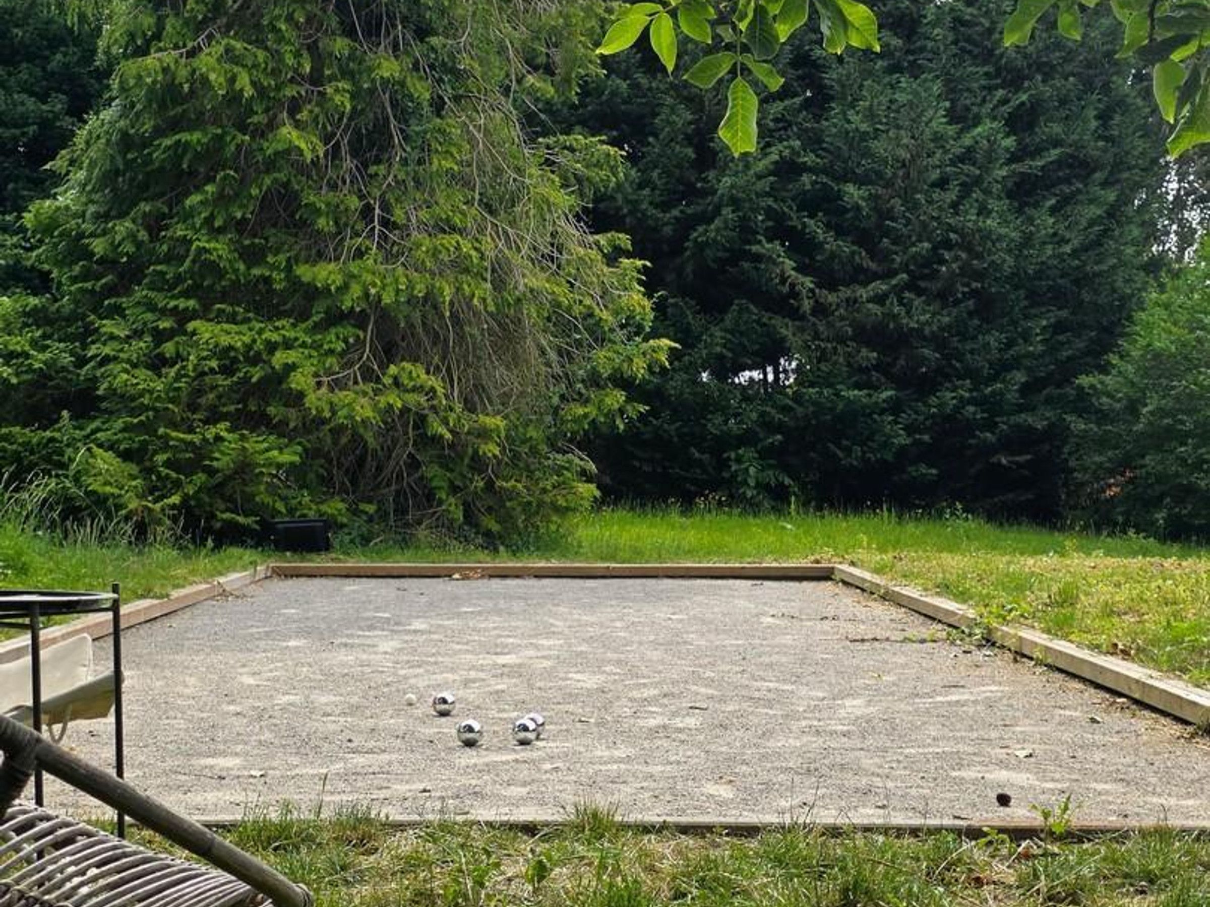Un espace extérieur carré, doté d’une surface en béton, entouré de pelouse et d’arbres.