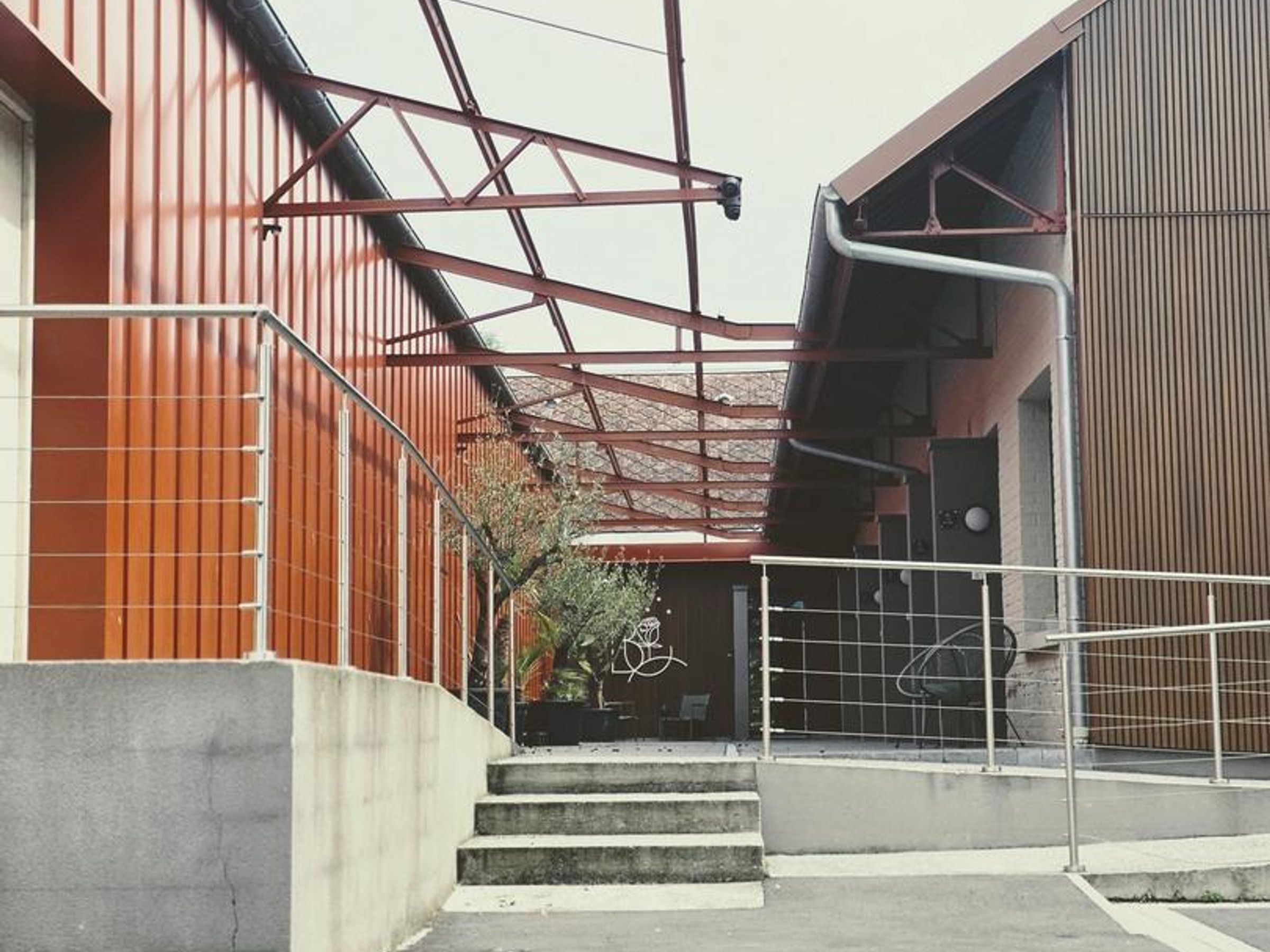 Een trap die leidt naar een gebouw met een metalen constructie en een betonnen fundering.