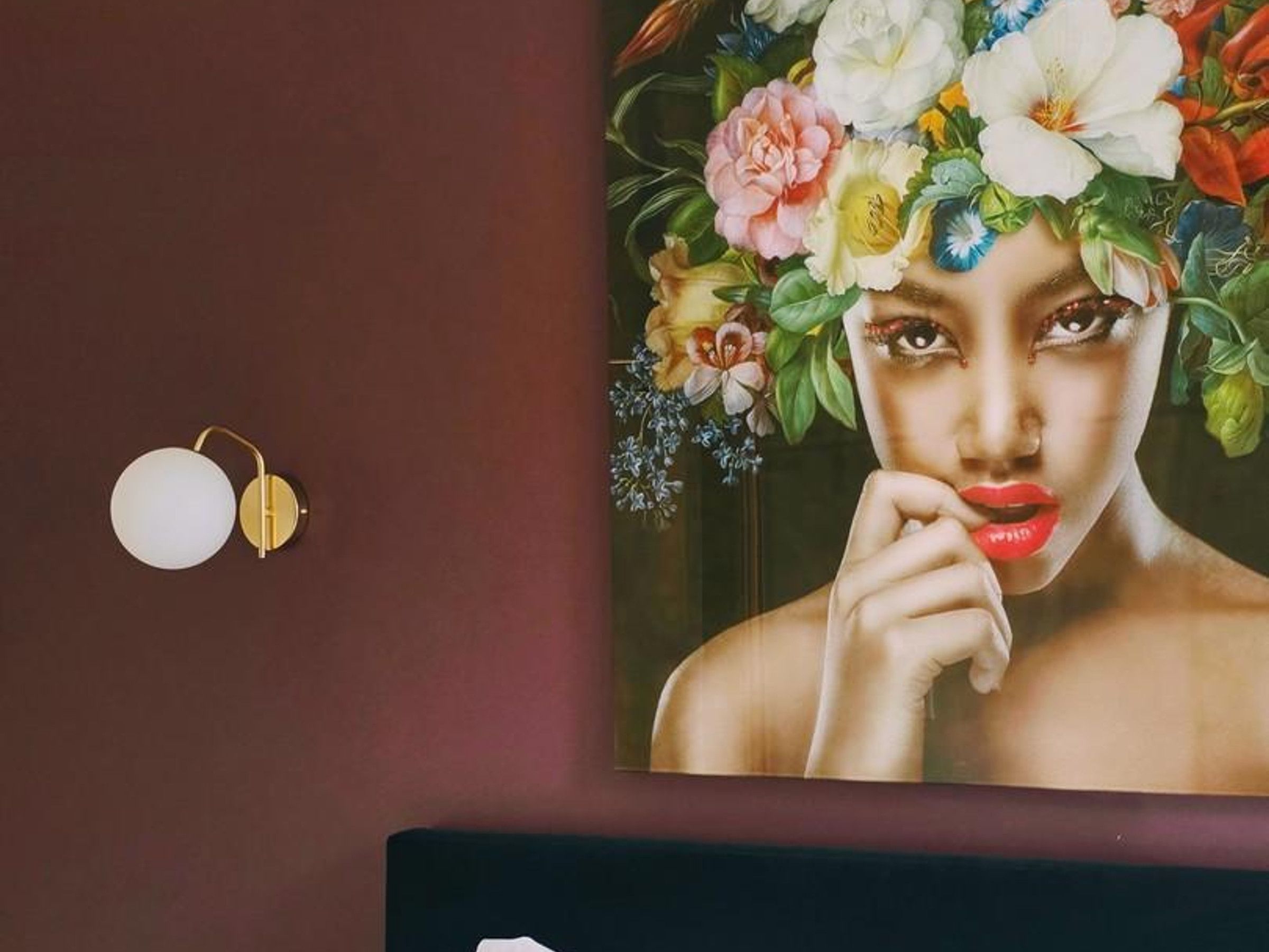 A wall with a framed artwork and a wall-mounted light fixture.