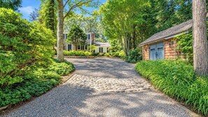 A gravel pathway leading to a house surrounded by lush greenery. - Serene Water Mill Retreat with Hot Tub, Farm Views, & Lush Gardens, Perfect... (Water Mill)